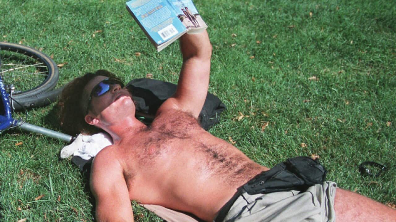 A man reads a book in the sun.