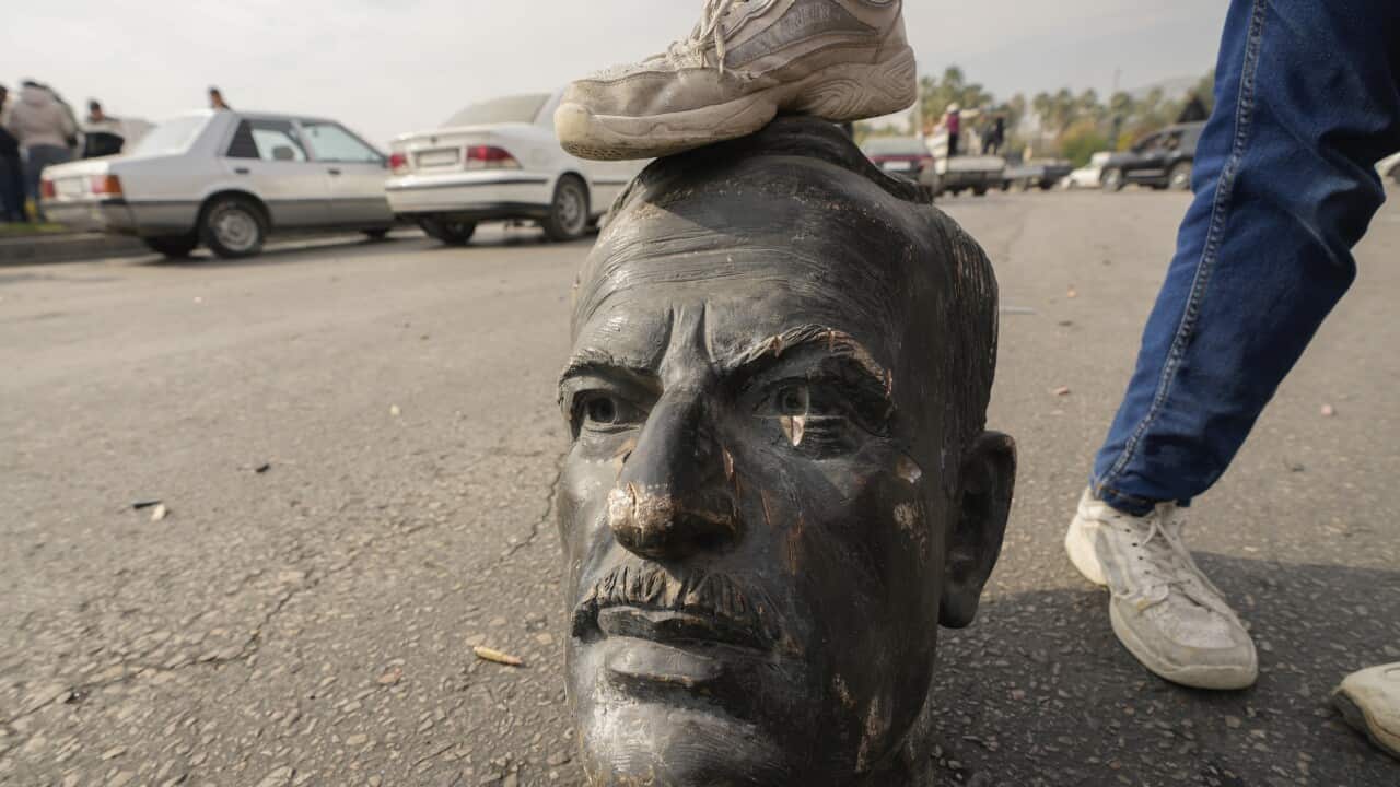 An opposition fighter steps on a broken bust of the late Syrian President Hafez Assad (AAP)