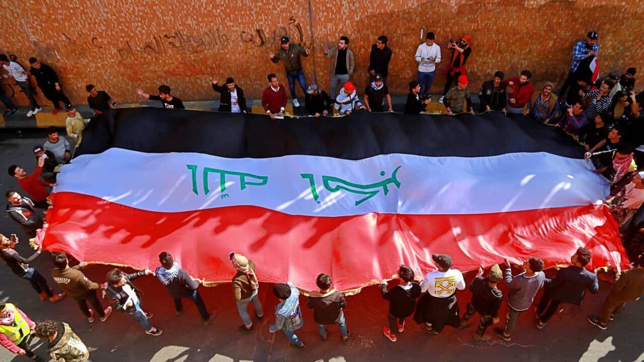 Students and other demonstrators hold national flags and chant slogans during a protest to condemn the militia attack on Najaf protesters