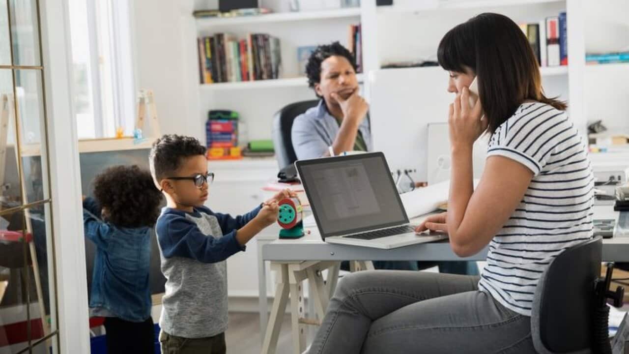 Parents working in home office with children playing