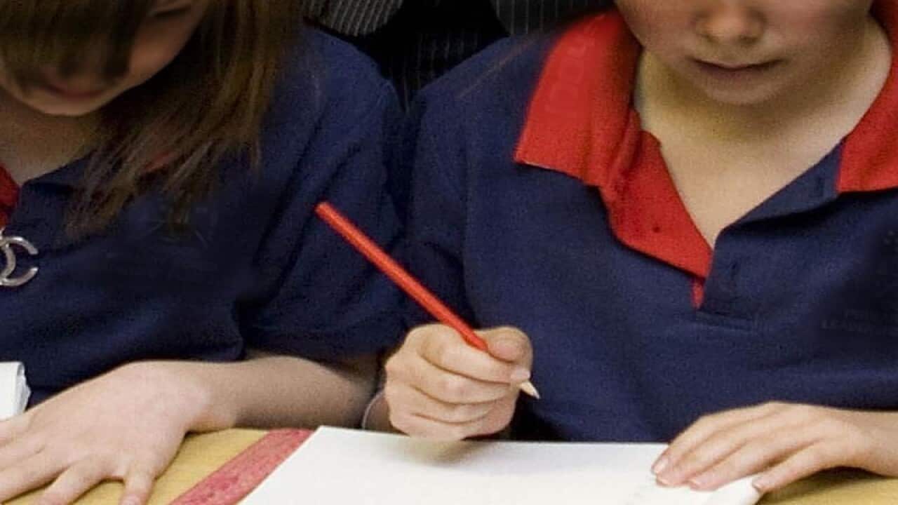 This is a file image of two school students writing.