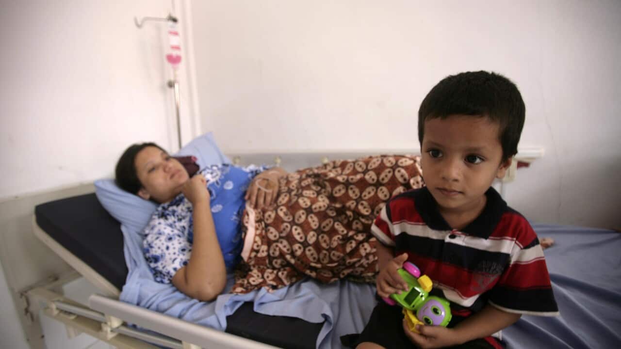 (left) An asylum seeker from Myanmar lying on a bed with her (right) son