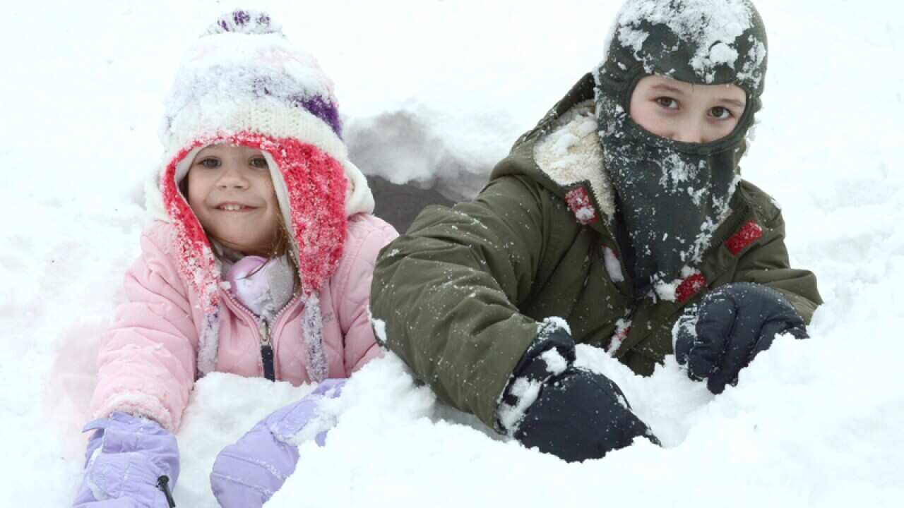 Children play in snow in the front yard of their home