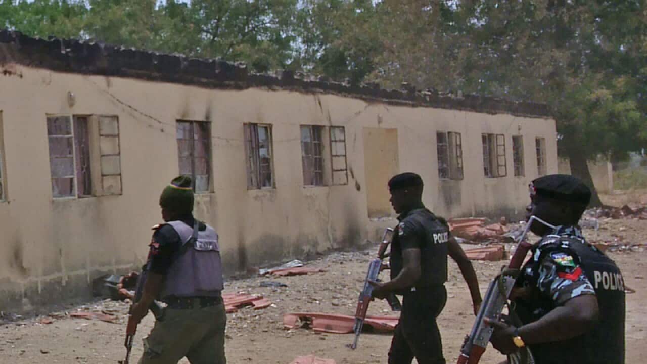 security walk past a burnt out building in Nigeria