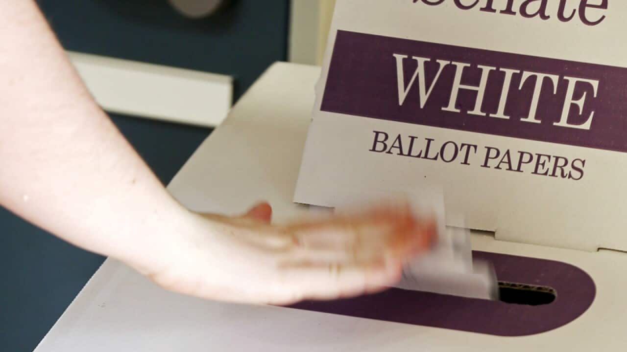 A voter drops a ballot at a polling booth