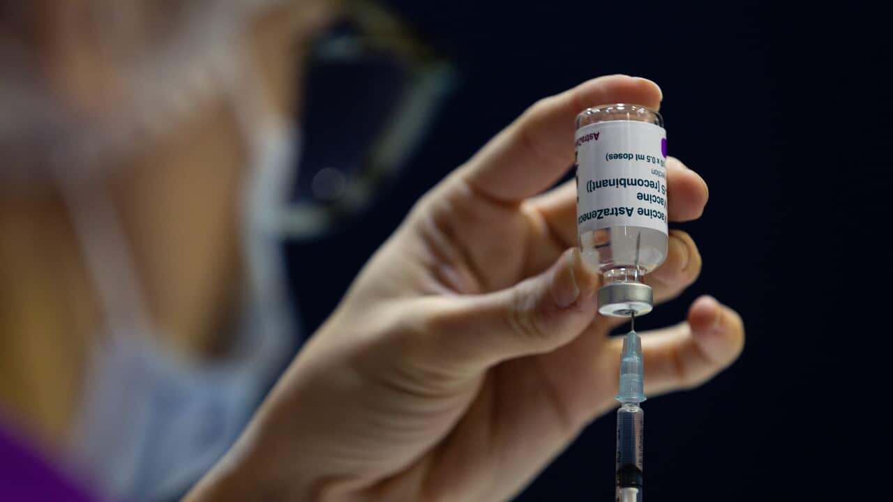 A nurse fills a syringe with a vaccine.