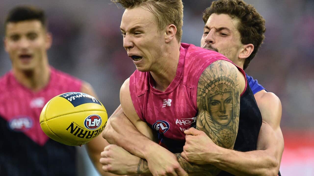 James Harmes of the Demons (left) is tackled by Tom Liberatore