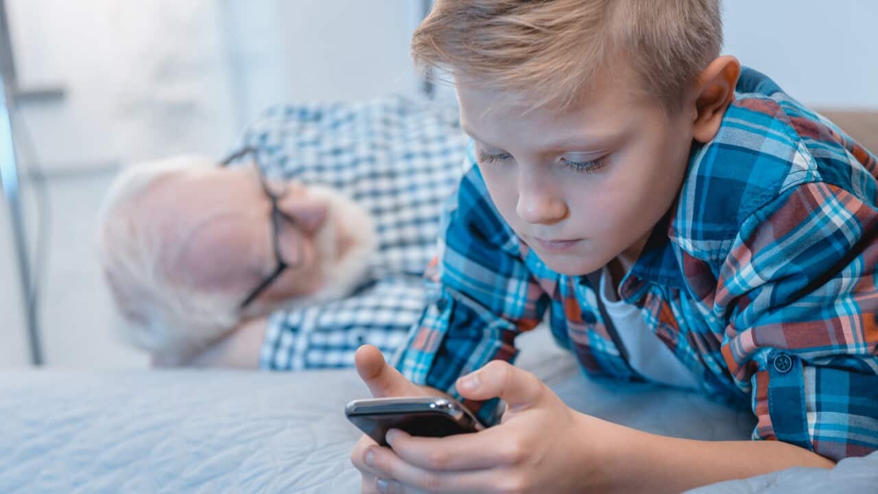 Little boy using smartphone on bed