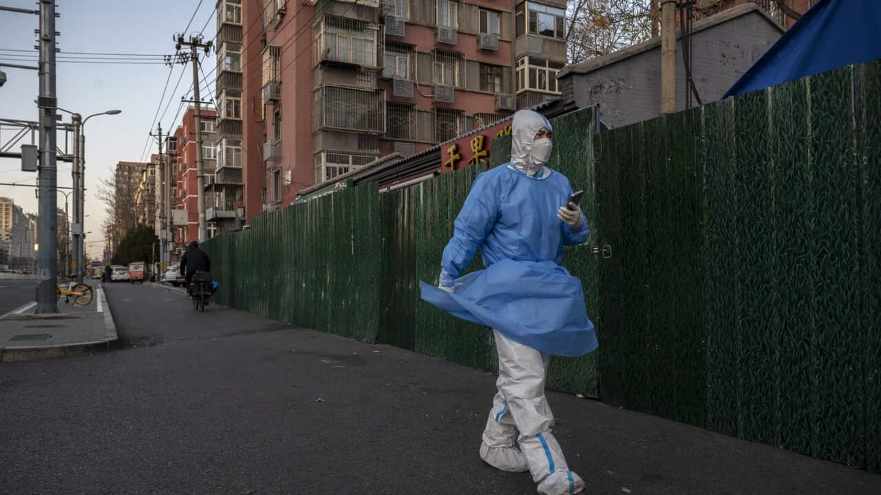 An epidemic control worker walks by a barricade outside a community under lockdown
