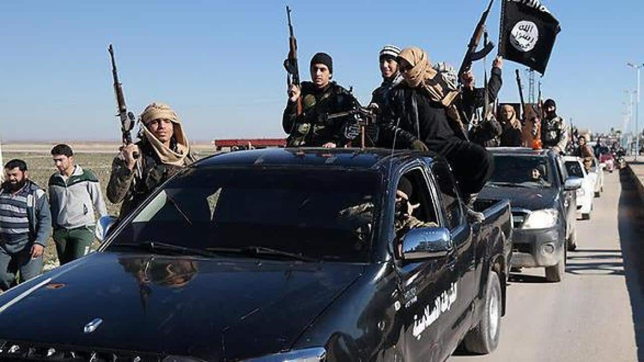 In this photo released on May 4, 2015, Islamic State militants pass by a convoy in Tel Abyad town, northeast Syria.