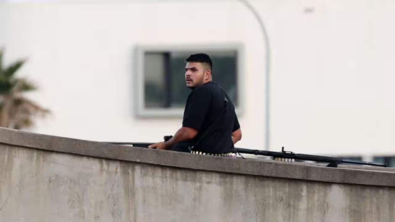A man with a shotgun on a bridge.