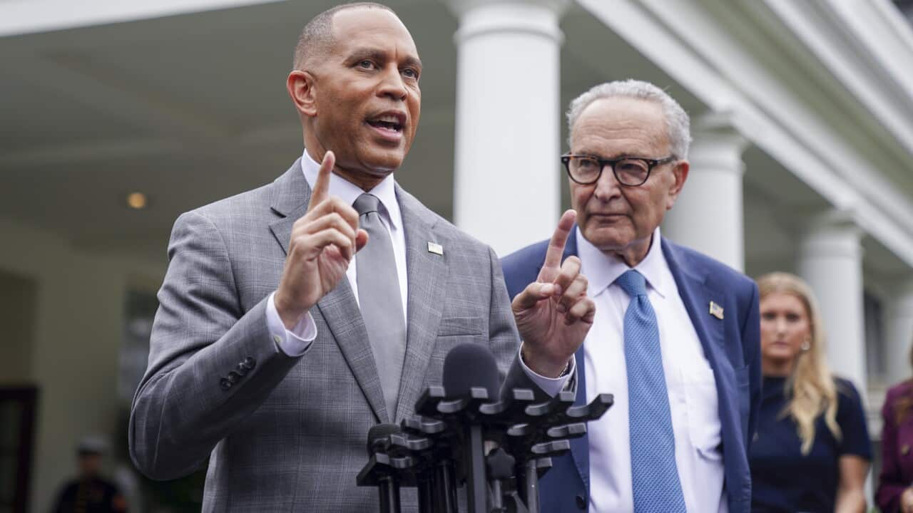 Two people wearing formal attire standing at a microphone. One is speaking.