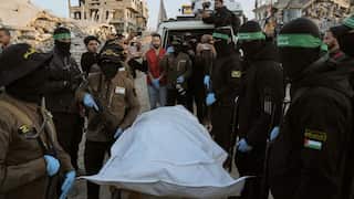 Masked and armed me stand around covered human remains