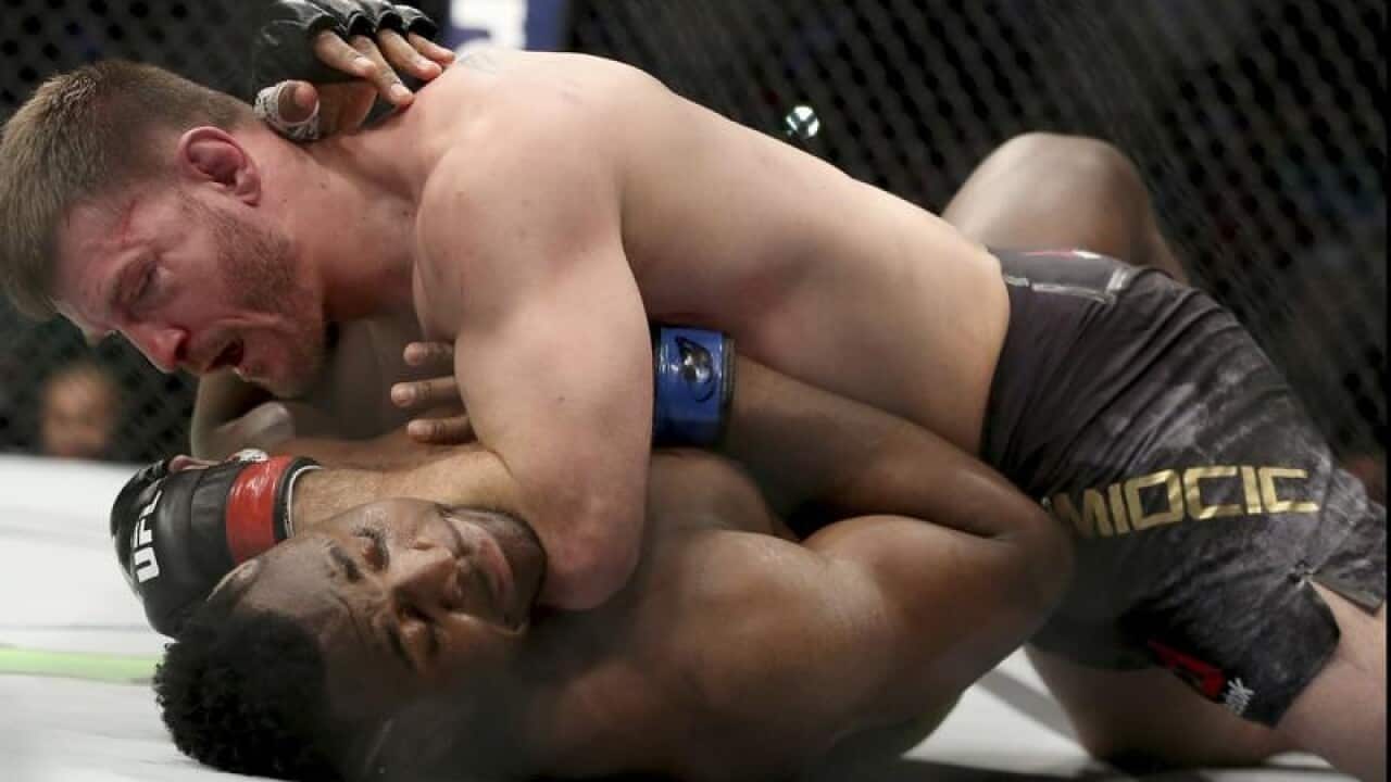 Stipe Miocic presses his elbow into the throat of Francis Ngannou