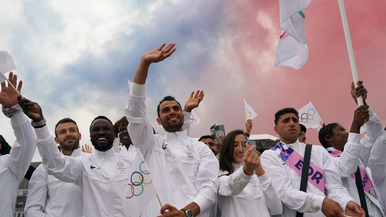 A group of people wave while some hold flags.