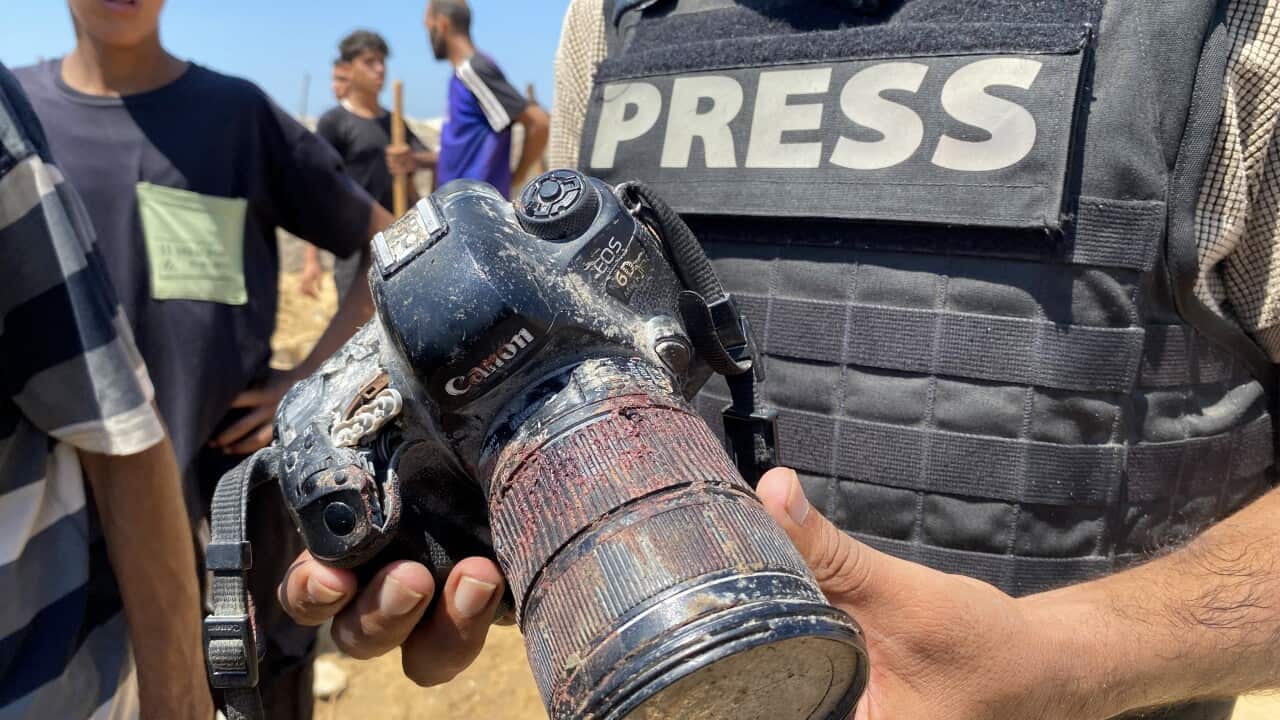 A man holds a blood-covered camera