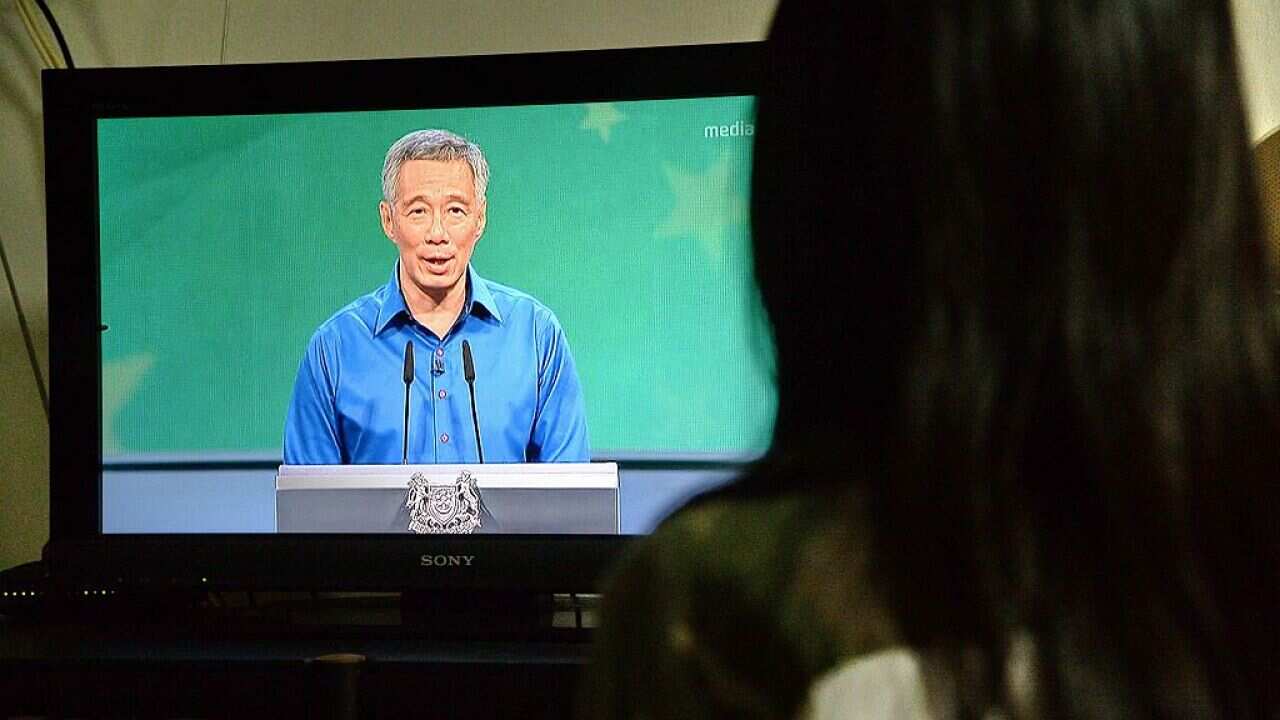 A Singaporean resident watches a live televised speech by Prime Minister Lee Hsien Loong after he became ill during a National Day Rally on August 21, 2016.