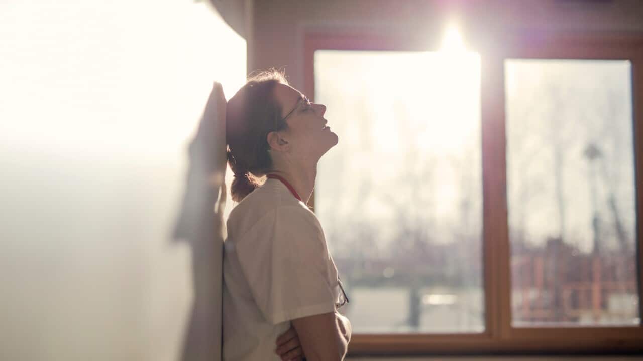 Exhausted health care worker leans against a wall