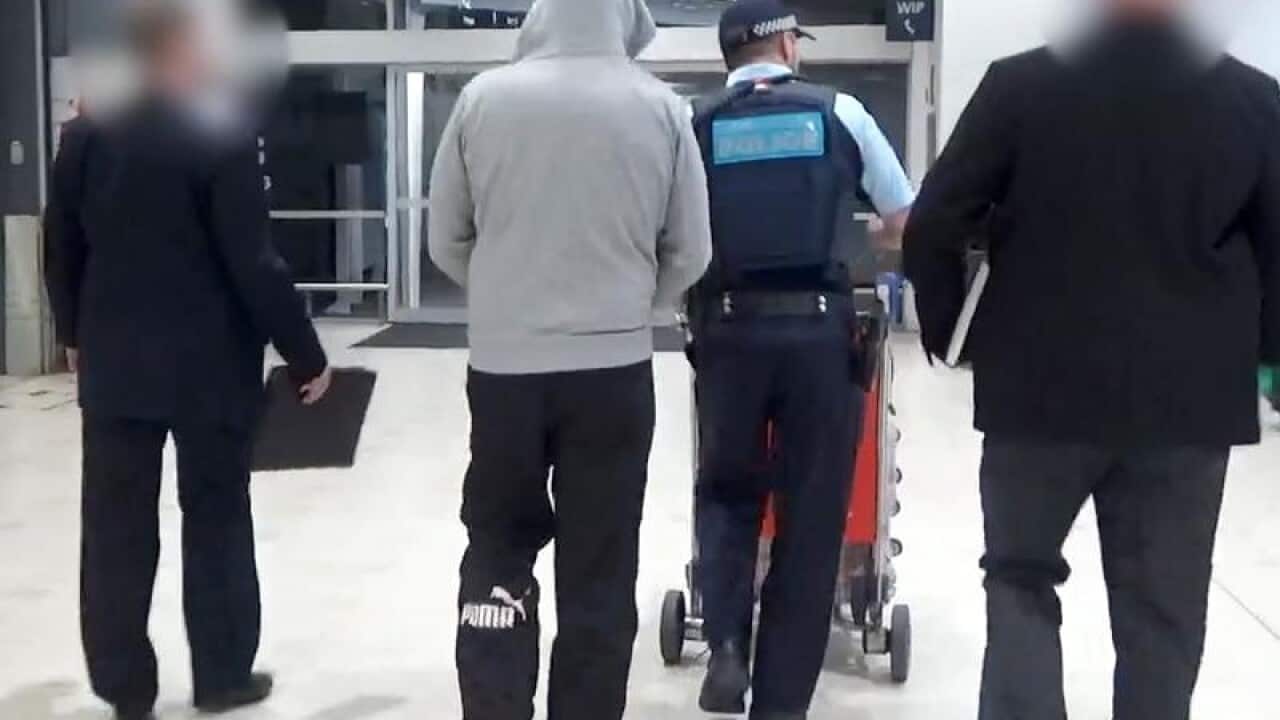 A man (second left) under AFP escort after extradition from Serbia.