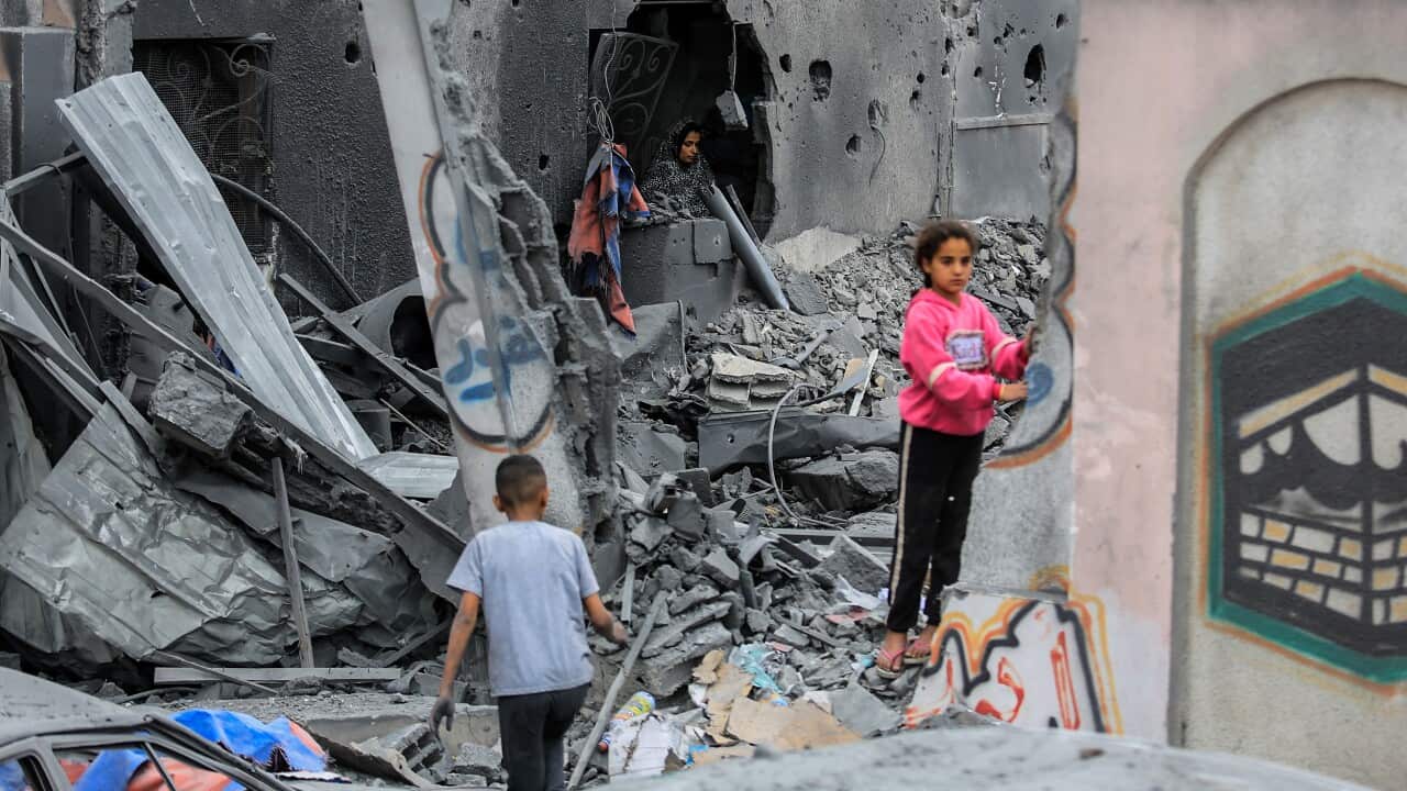 Palestinian residents inspect destroyed building and collect usable items after an Israeli attack