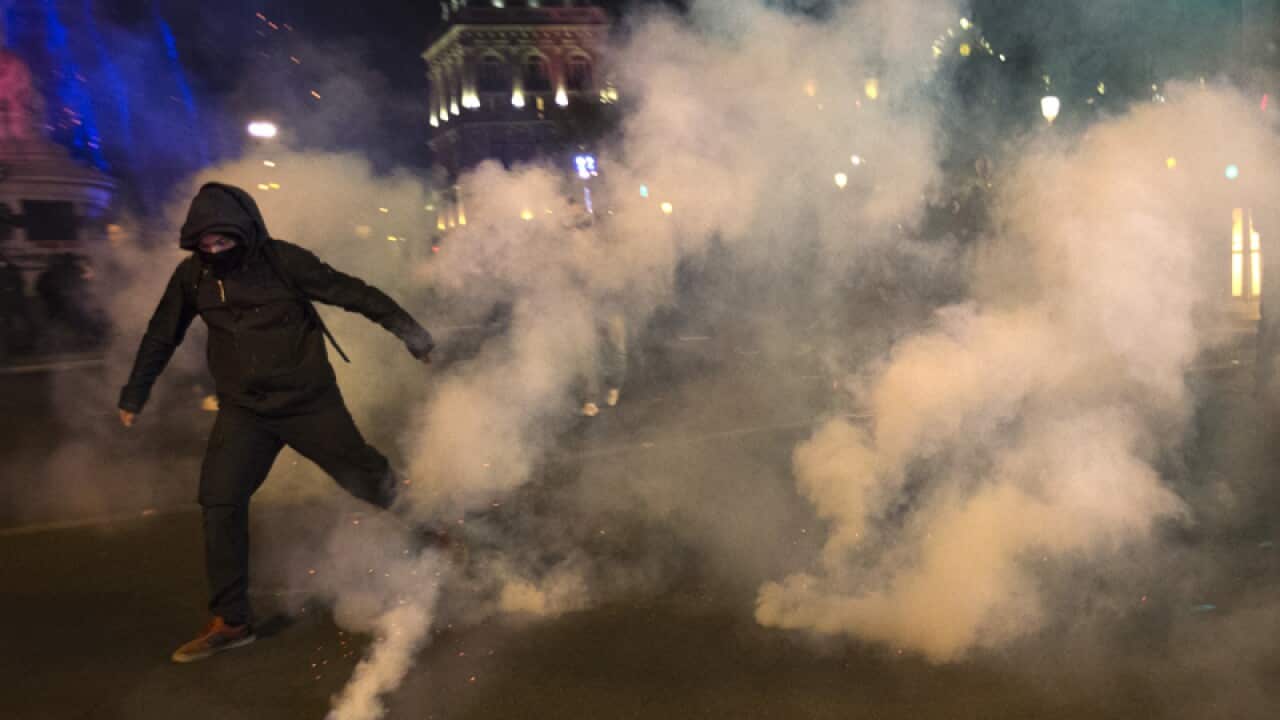 A demonstrator runs from tear gas during clashes with police in Paris