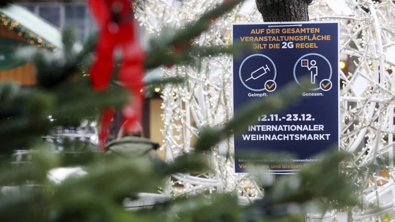 A sign indicating COVID-19 restrictions, where access is allowed only for people who are vaccinated or recovered and tested, hangs at the entrance of a Christmas market in Essen, Germany, Wednesday, Nov. 24, 2021.(Roland Weihrauch/dpa via AP)
