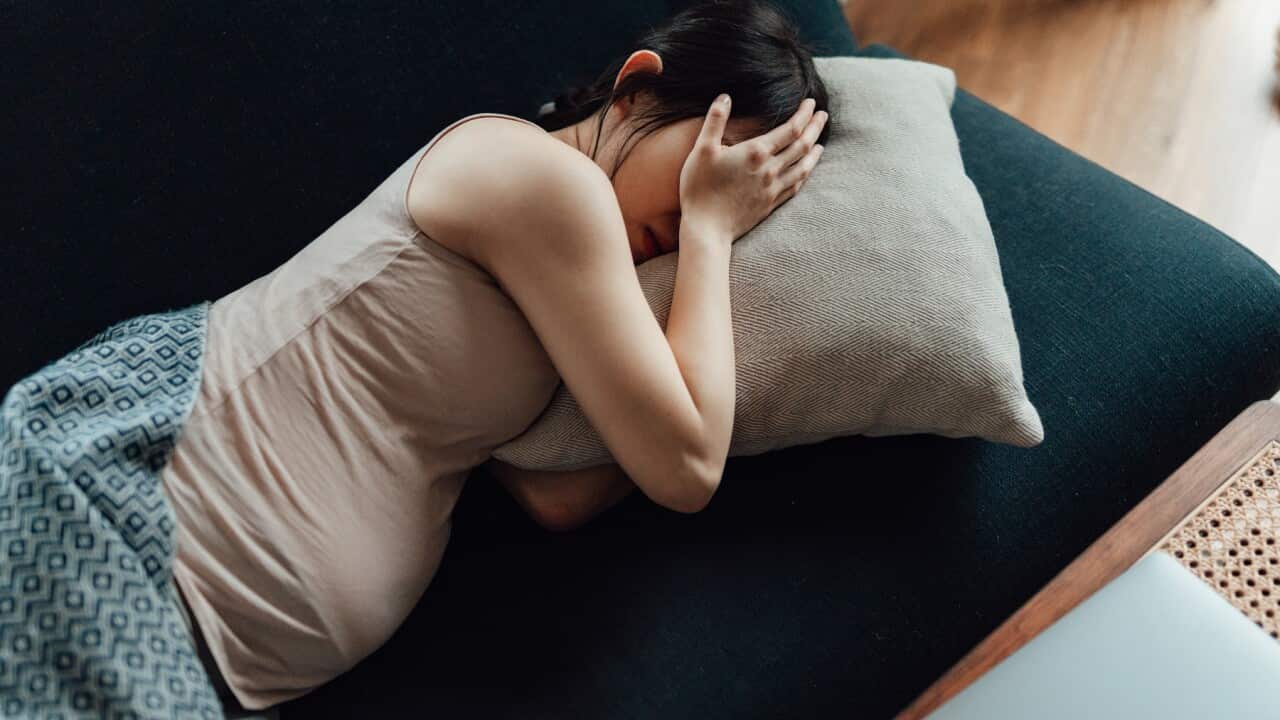 Pregnant Woman Covering Her Eyes With Hands While Laying On Sofa