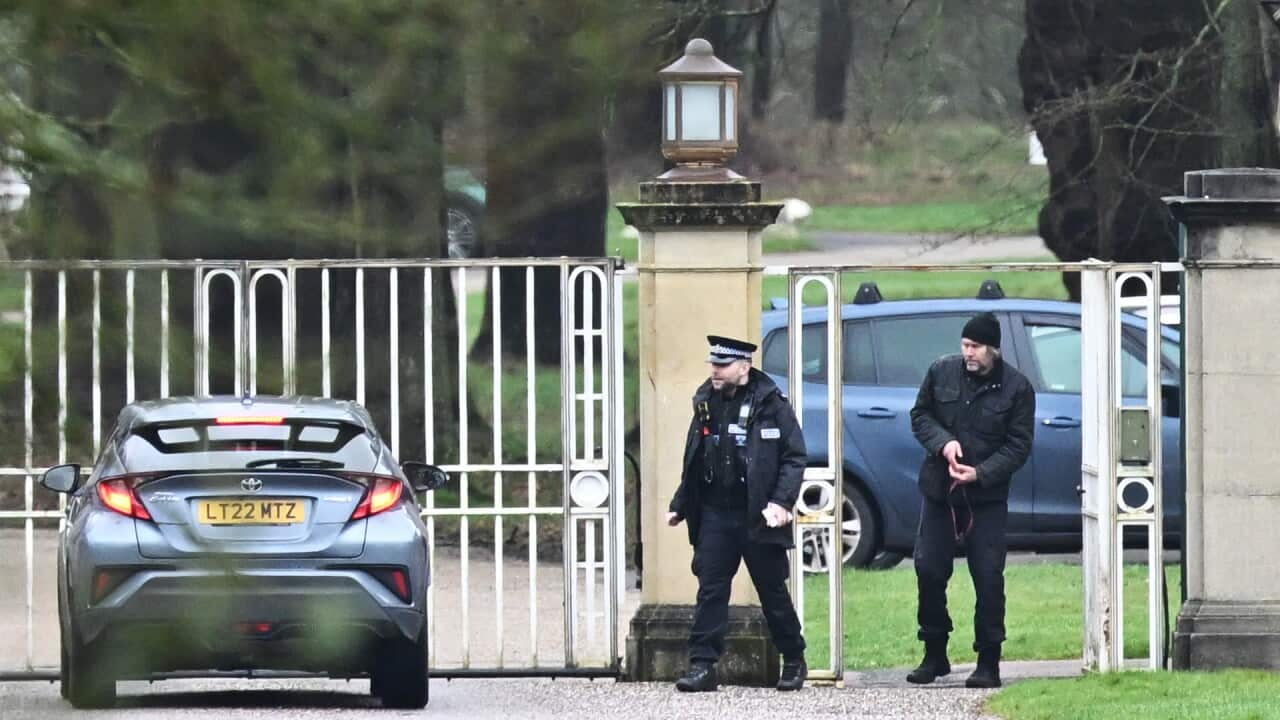 Police officers standing by a gate with a car parked nearby