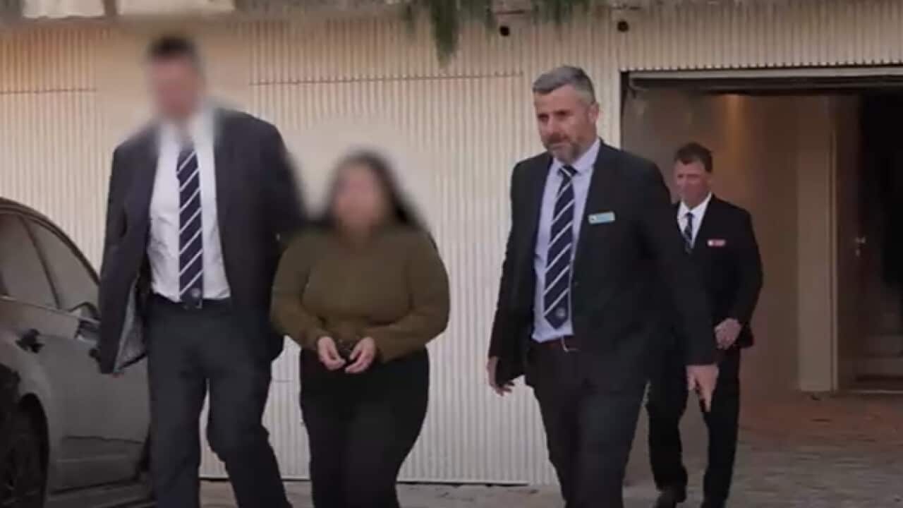 Police officers escorting a woman from a property.
