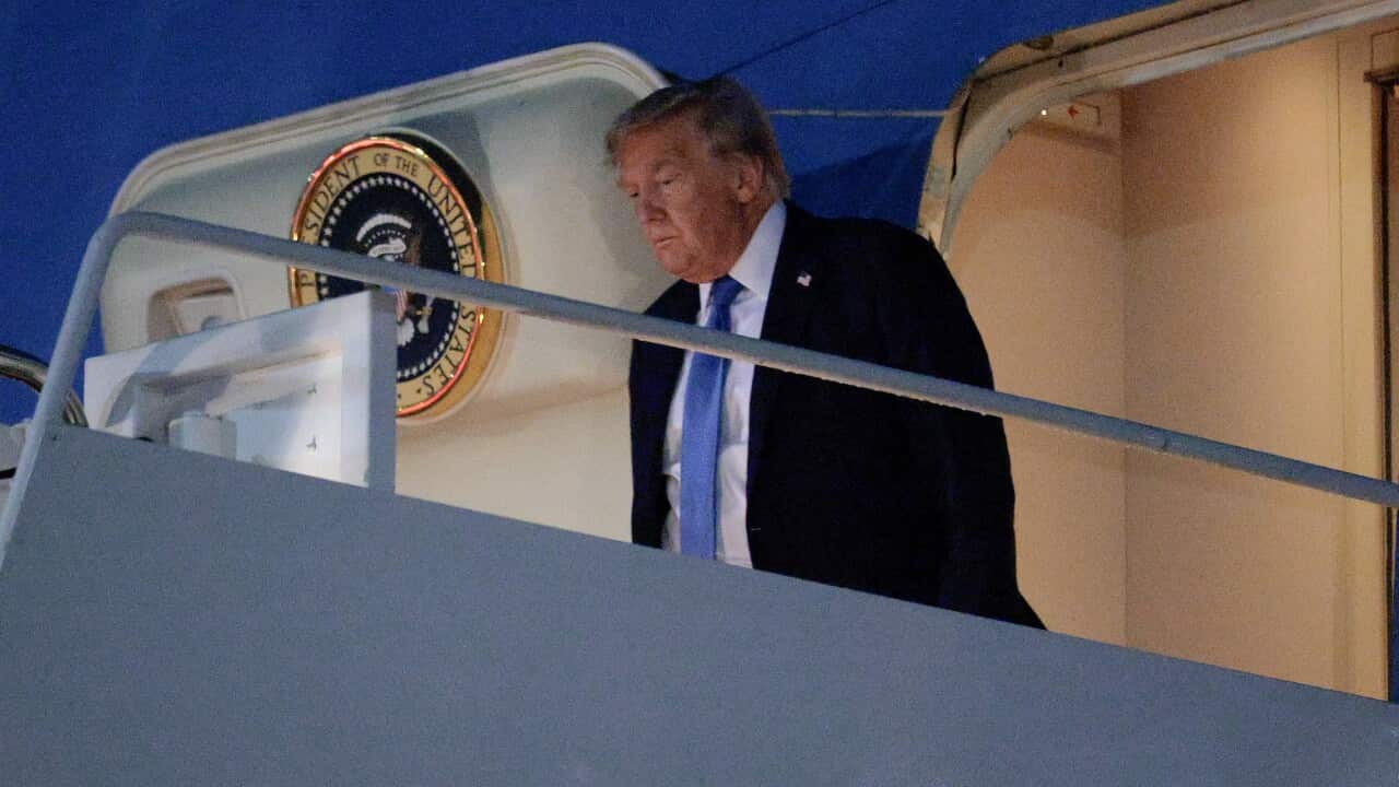 Donald Trump walks out the door of a plane emblazoned with the US presidential coat of arms.