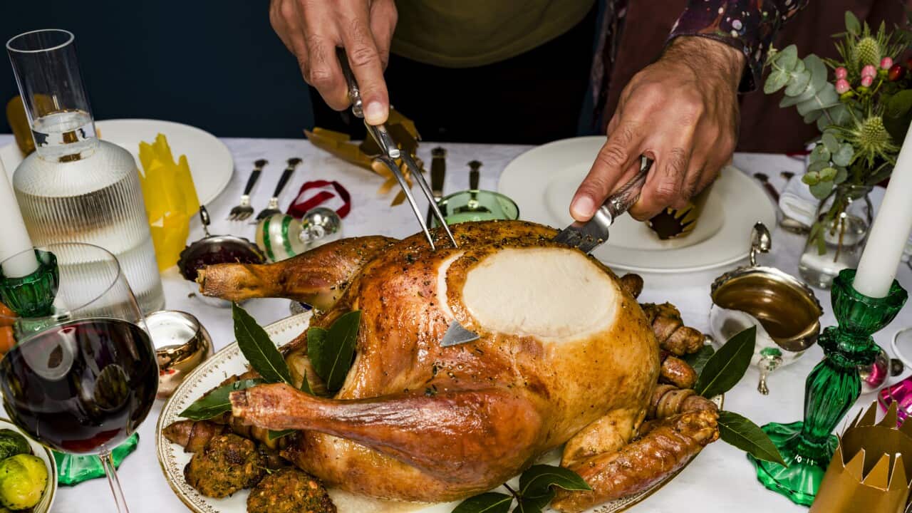 Man carving roasted turkey at traditional Christmas table