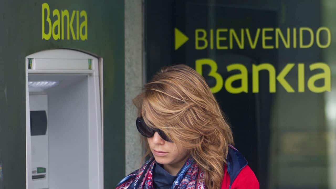 A woman uses an ATM cash point machine at a branch of the Bankia bank in Madrid