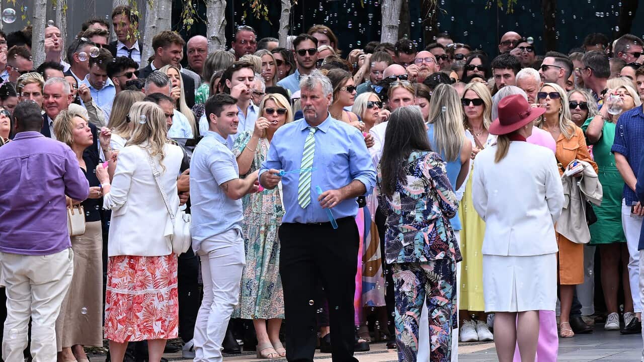 People gathered in a crowd blowing bubbles.