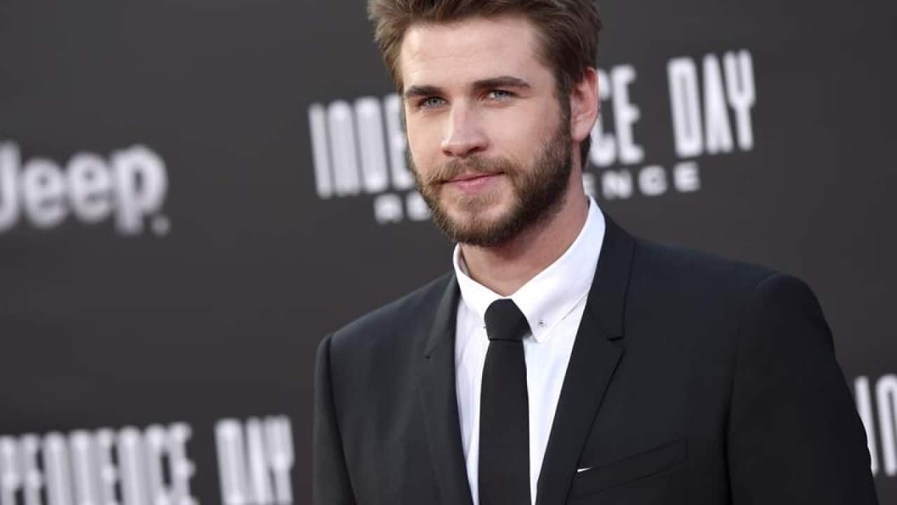 Liam Hemsworth arrives at a movie premiere.