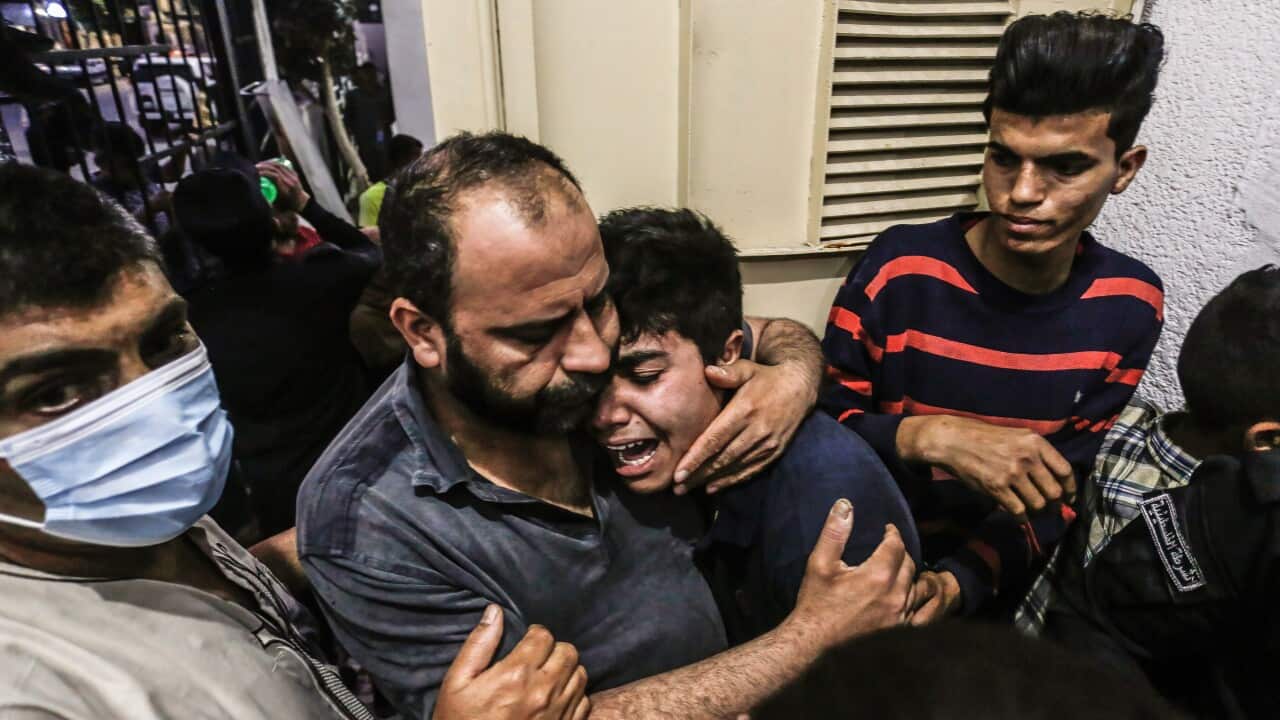 A Palestinian boy with his father cries following the deaths in Israeli-Palestinian violence.