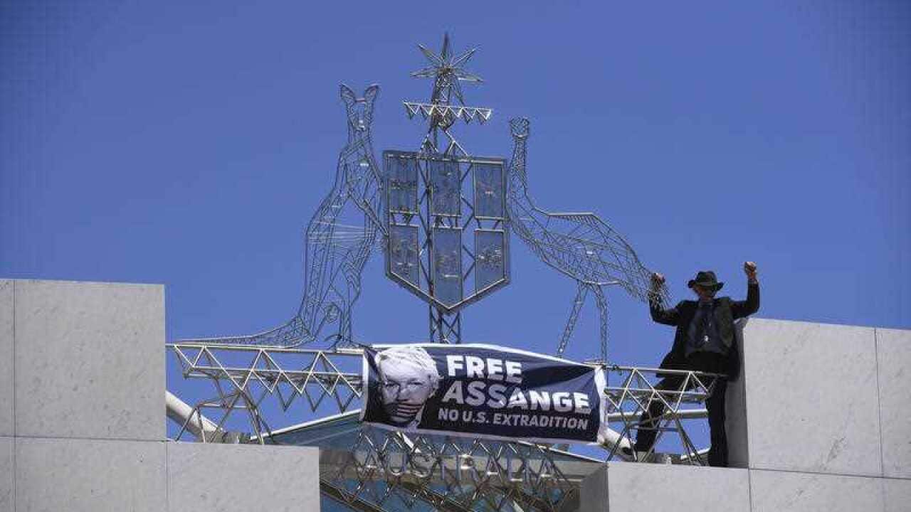 A protester demanding the release of Julian Assange is seen on top of Parliament House in Canberra.