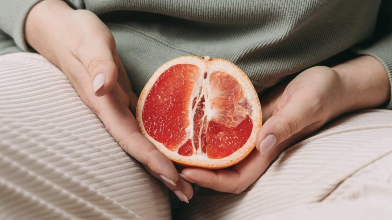 A woman holding a piece of fruit