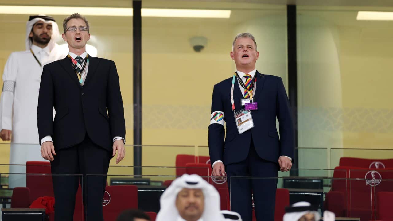 Two mean wearing suits and ties standing up.
