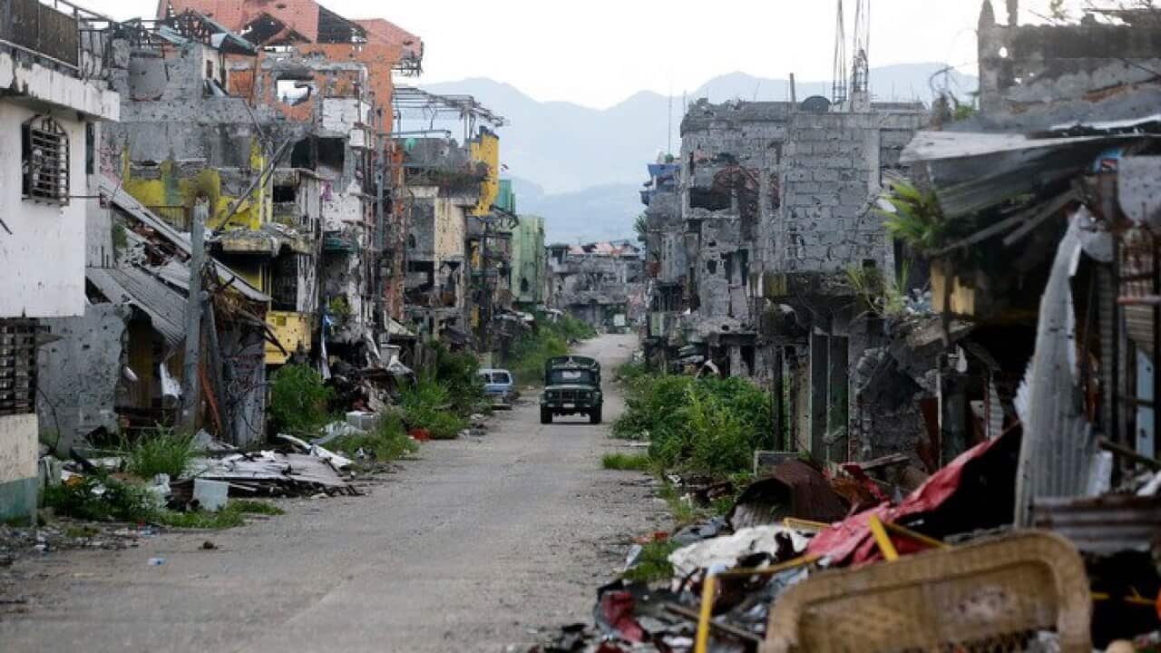A military vehicle drives down a road in the devastated city of Marawi