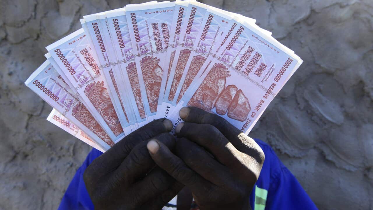 A man holds a handful of 5 Billion Zimbabwean dollar notes (AP Photo/Tsvangirayi Mukwazhi)