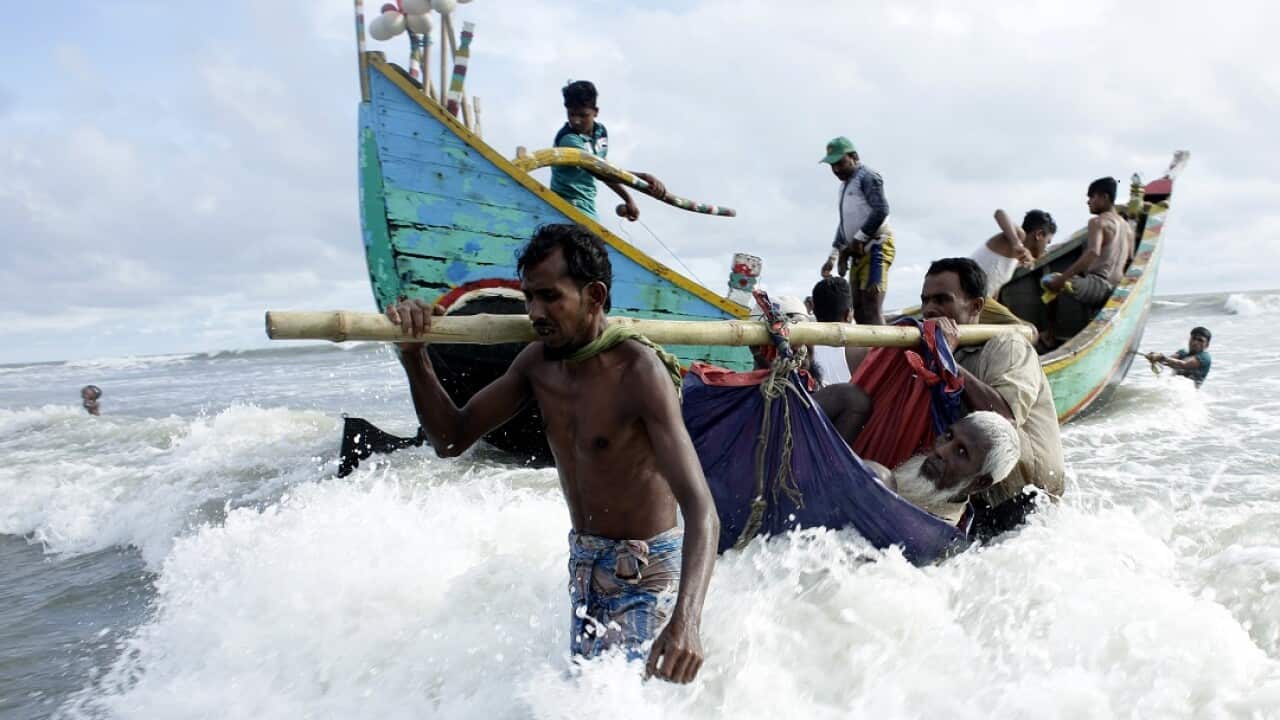 Rohingya refugees carry an old man towards the shore of Naf river as people arrive by boats in Bangladesh.