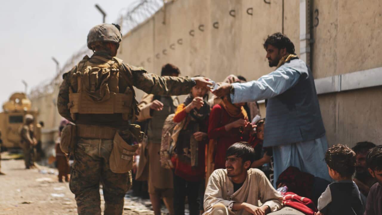 A soldier passes out water to evacuees near Hamid Karzai International Airport, Kabul, Afghanistan.