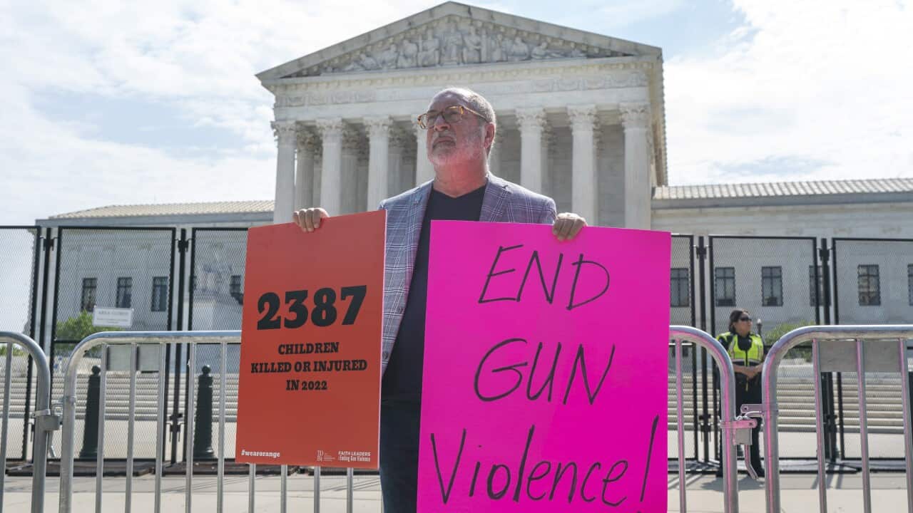 A bald man stands outside the US Supreme Court holding a sign reading "end gun violence"