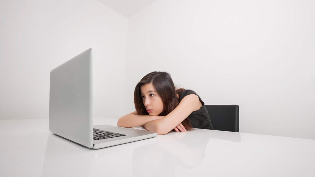 Bored young businesswoman looking at laptop in office