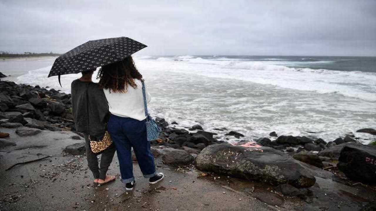 Two women watch stormy conditions at Byron Bay, NSW, on 14 December, 2020.