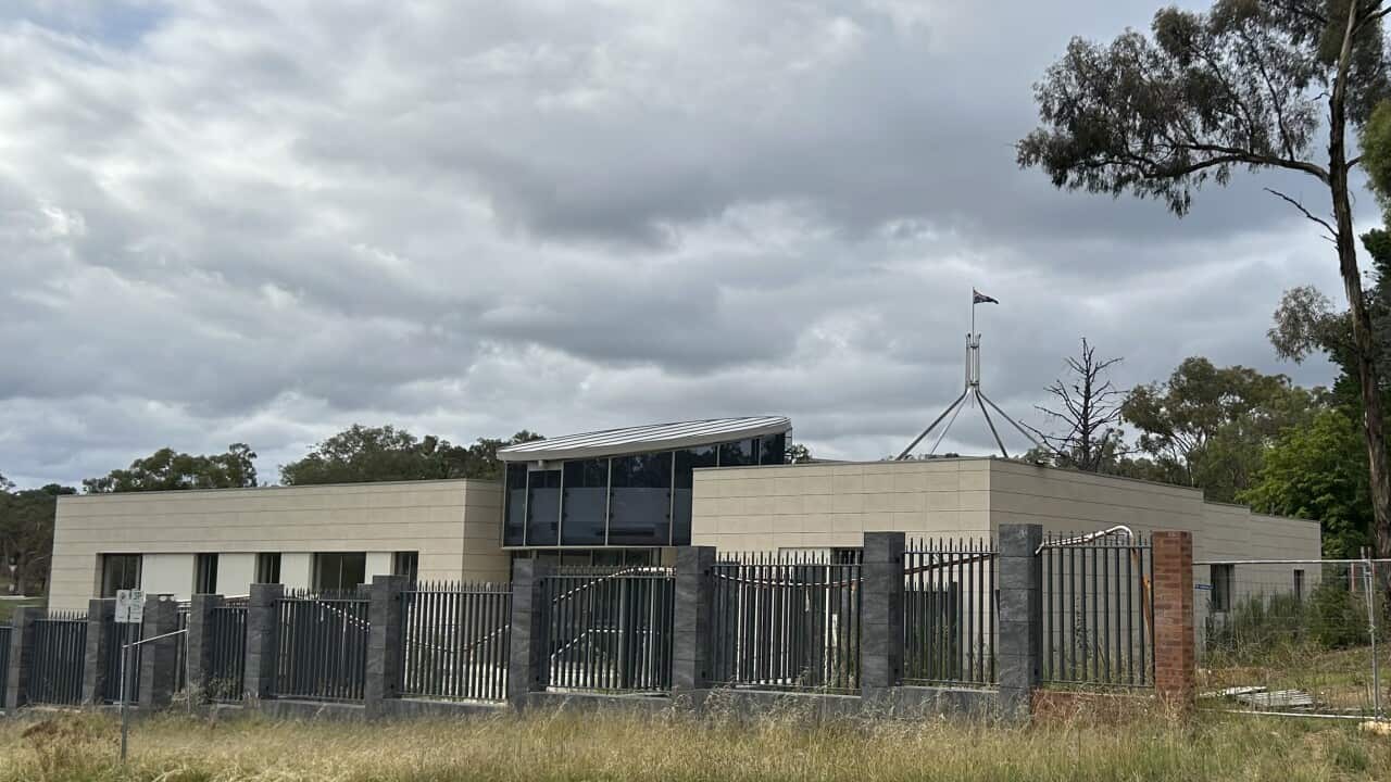 A partially built building behind a fence.