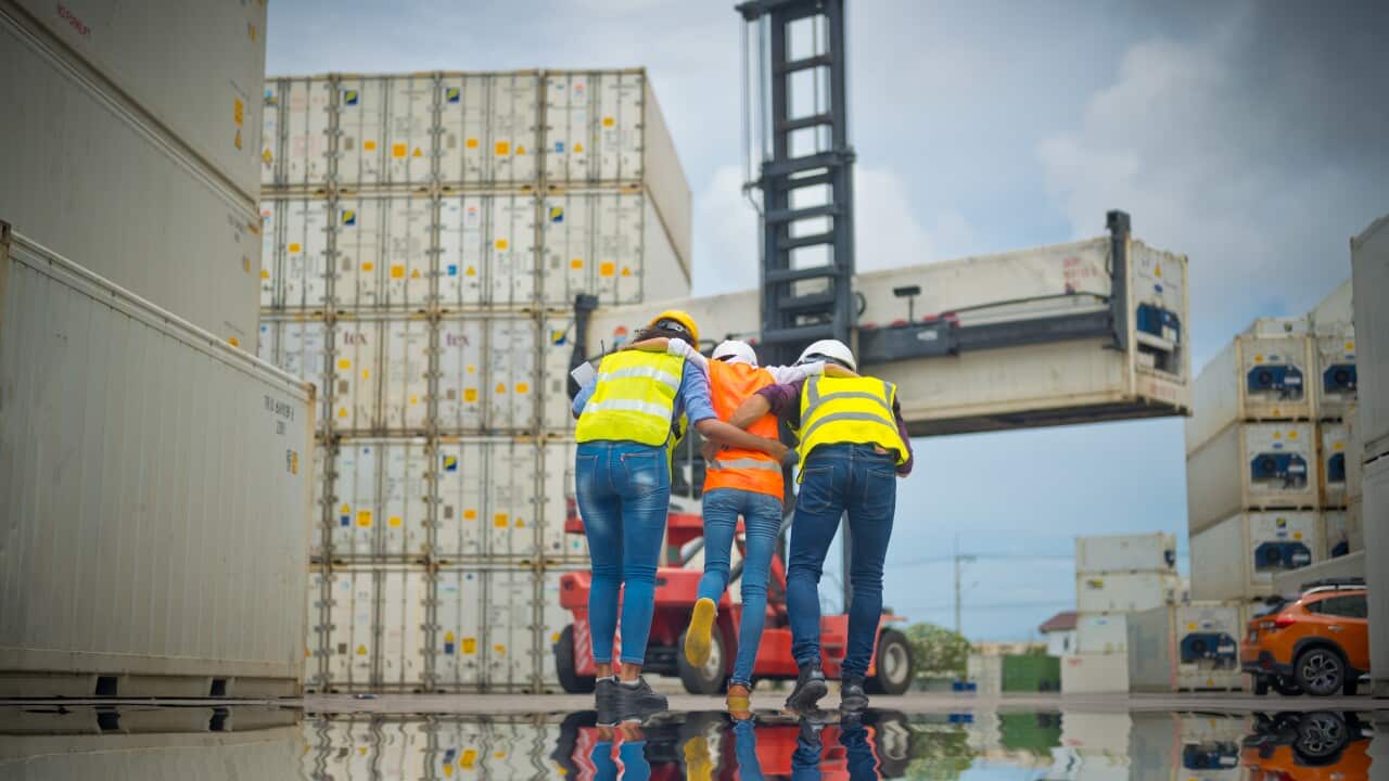 A person in a hi-vis suit who has been injured being helped to walk by two other workers in hi-vis gear.
