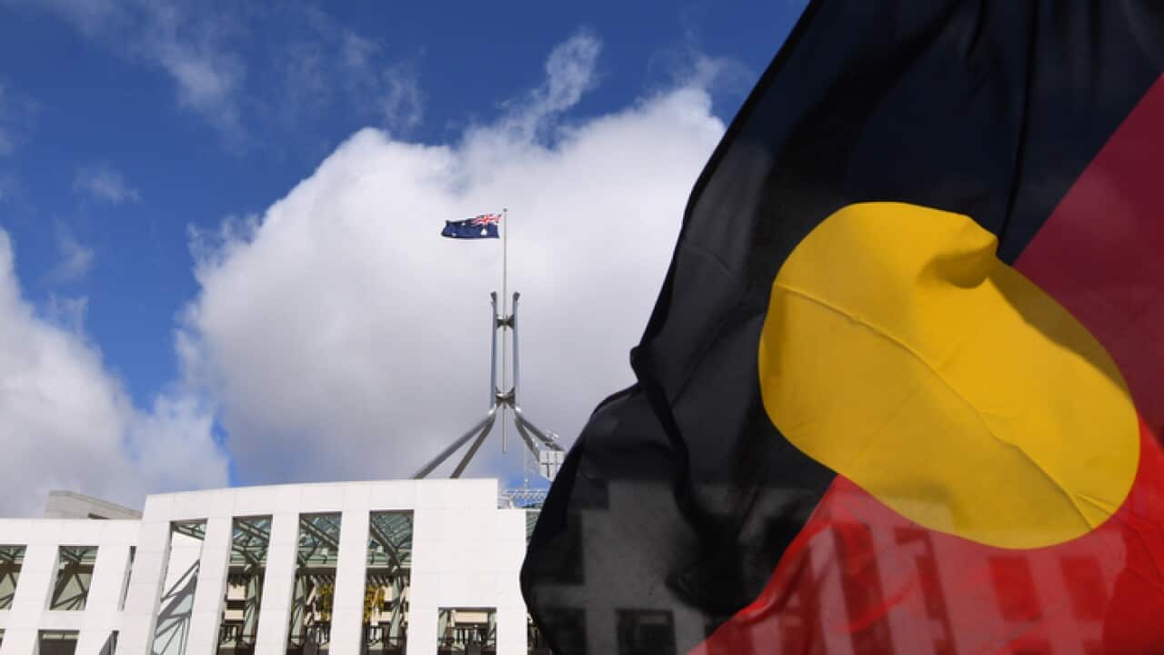 Australian Parliament House is seen through an Aboriginal flag in Canberra, Tuesday, September 5, 2017. (AAP Image/Lukas Coch) NO ARCHIVING