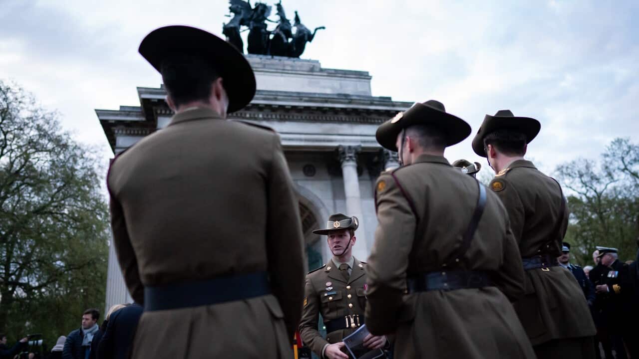 Four soldiers stand in front of a war memorial.