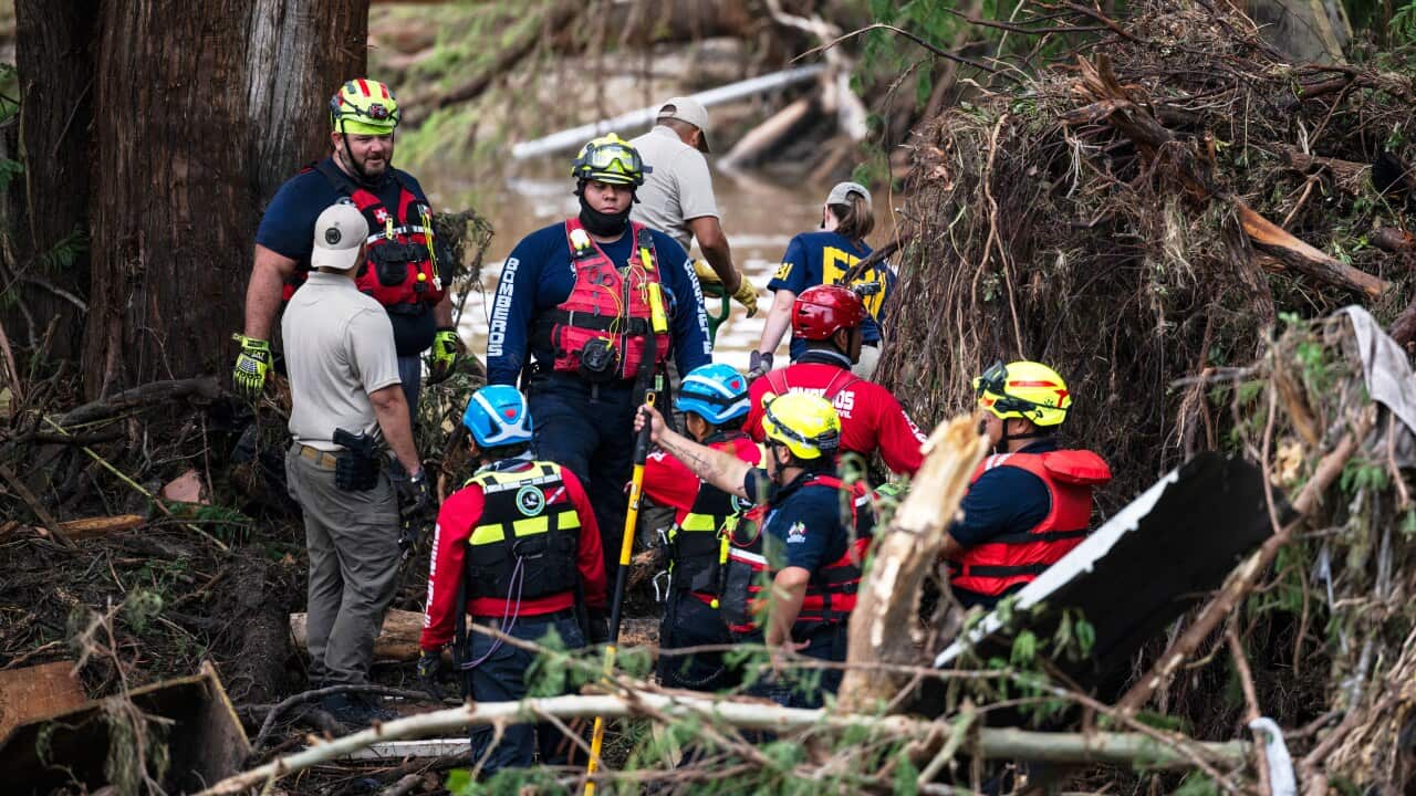 Emergency personnel gathered at a site strewn with fallen trees after it was struck by extreme weather.